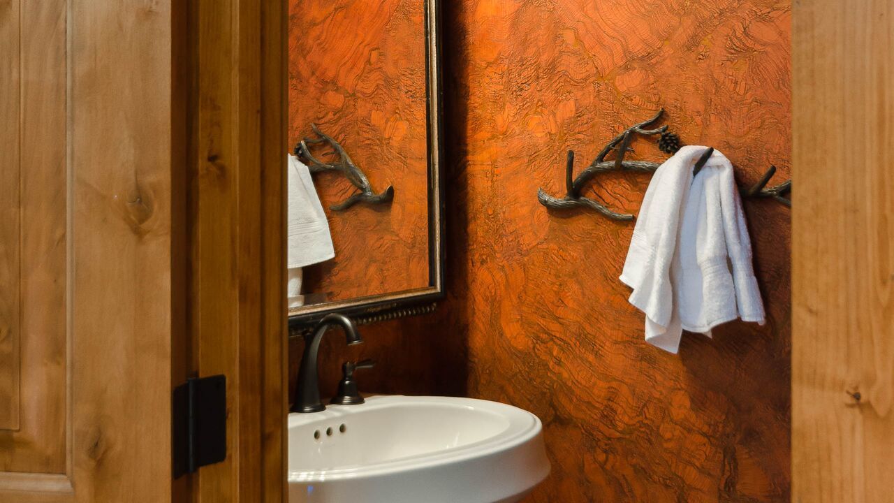 A bathroom with a wooden wall, a white sink, and a mirror.