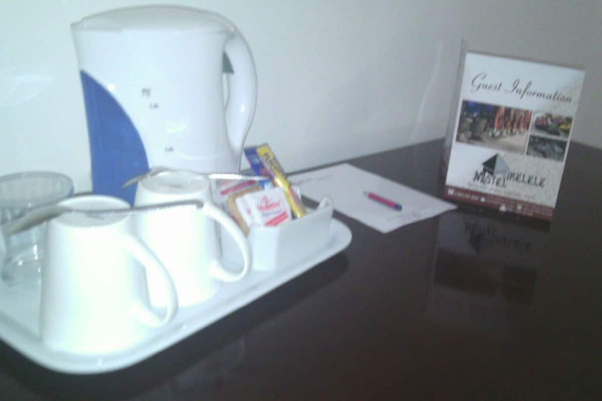 Una bandeja con tazas de café, una tetera y un pequeño recipiente con cubitos de azúcar sobre una mesa.