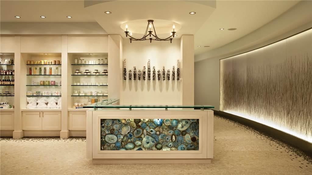 A modern interior with a central display case, shelves with various items, and a decorative wall with a textured pattern.