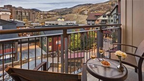 A balcony with a table, two wine glasses, and a vase with flowers. - Farwell Mountain 607 4 BedroomCondo By Moving Mountains (Steamboat Springs)