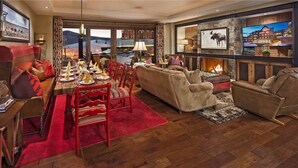 A cozy living room with a fireplace, red upholstered furniture, and a dining area with a red carpet.