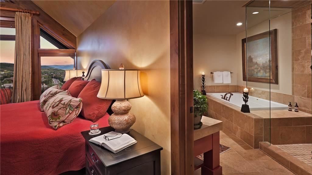 Een hotelkamer met een bed, nachtkastje, lamp en uitzicht.