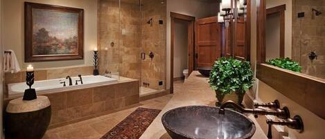 A modern bathroom with a large bathtub, a freestanding basin, and a glass-enclosed shower.