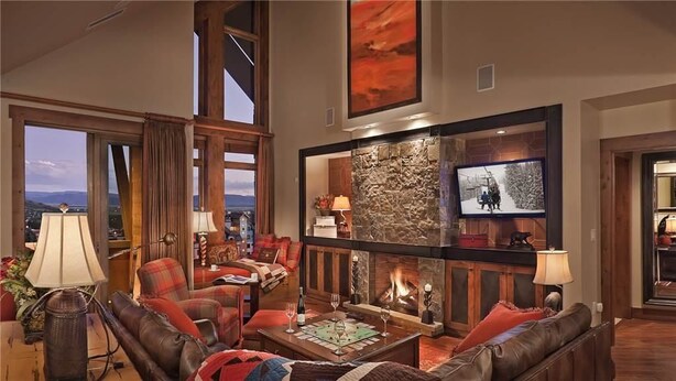 A spacious living room with a fireplace, comfortable seating, and a large window offering a scenic view. - Diamond Peak Penthouse 616 4 BedroomCondo By Moving Mountains (Steamboat Springs)