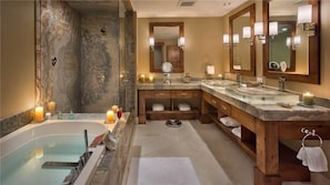 Ein Badezimmer mit einer großzügigen Badewanne, zwei Waschbecken und einem Waschtisch mit Spiegel.