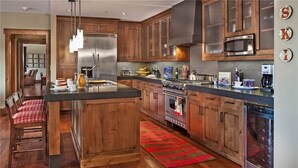 A modern kitchen with wooden cabinets, stainless steel appliances, and a central island. - Emerald Mountain 702 4 BedroomCondo By Moving Mountains (Steamboat Springs)