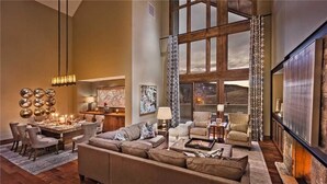 A spacious living room with a large window, a dining area, and a cozy seating arrangement. - Quandary Peak Penthouse 704 4 BedroomCondo By Moving Mountains (Steamboat Springs)