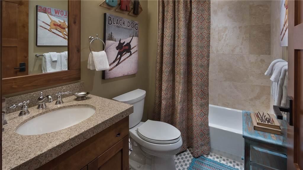 A bathroom with a sink, toilet, and bathtub. There are towels hanging on the wall and a shower curtain.