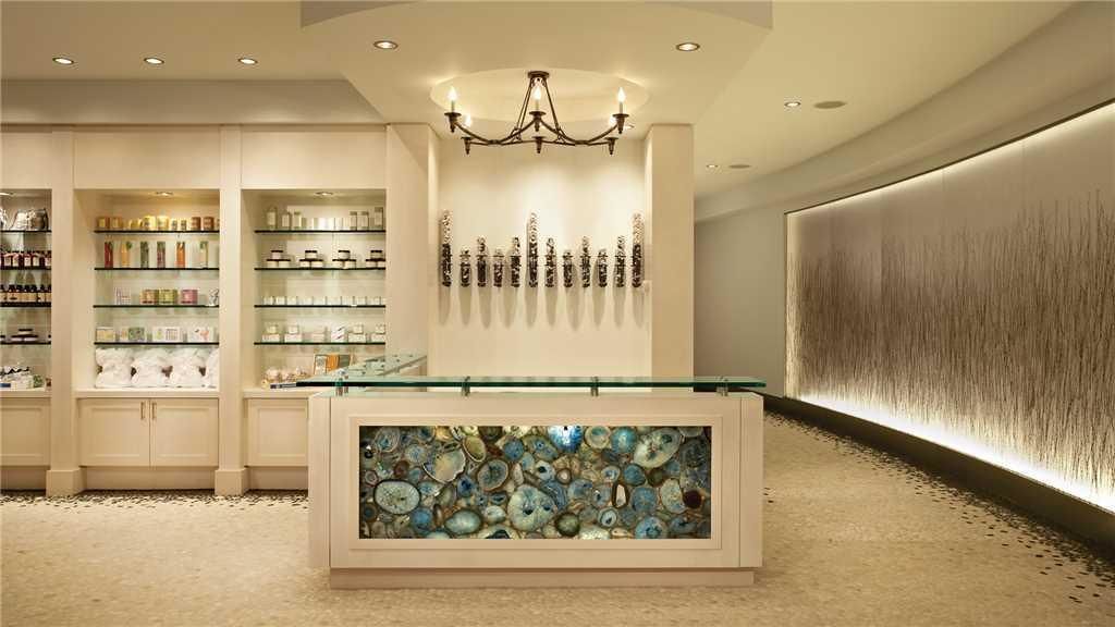 A modern interior with a central glass display case, shelves with various items, and a decorative wall with vertical elements.