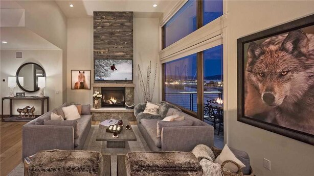 Amplia sala de estar con chimenea, asientos cómodos y grandes ventanales con vistas al exterior.