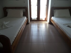 Una habitación de hotel con dos camas individuales, un cabecero de madera y piso de baldosas.