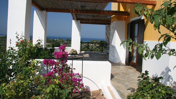 A white building with a balcony overlooking the sea, surrounded by greenery and bougainvillea flowers. - Ilis Villas (Andravida-Kyllini)