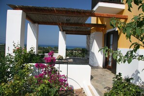 A white building with a balcony overlooking the sea, surrounded by greenery and bougainvillea flowers. - Ilis Villas (Andravida-Kyllini)