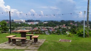 A picnic area with benches and a stone pathway, overlooking a residential area with houses and a distant view of a body of water. - MOTEL DESA (Kuala Terengganu)