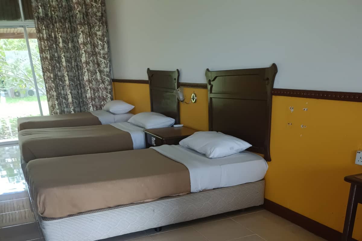 Une chambre d’hôtel avec deux lits, une petite table et une fenêtre avec des rideaux.