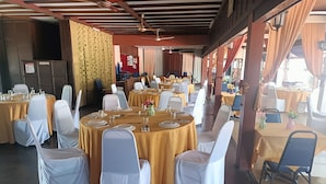 A banquet hall with round tables, white chairs, and yellow tablecloths. - MOTEL DESA (Kuala Terengganu)