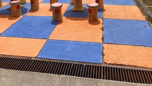 A pool area with a checkered floor, surrounded by tables and chairs. - MOTEL DESA (Kuala Terengganu)