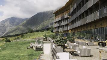 A modern building with outdoor seating and a view of mountains.