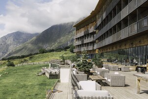 Un edificio moderno con asientos al aire libre y vistas a montañas.