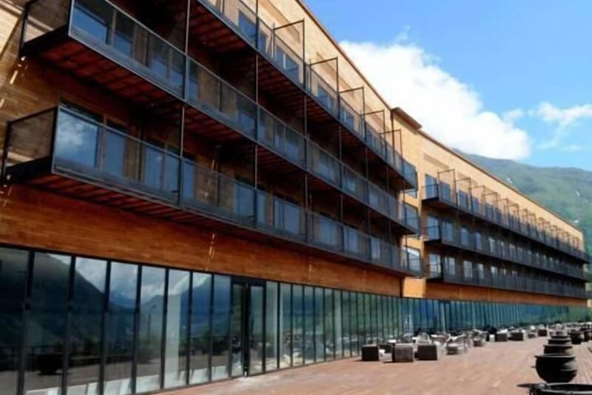 Um edifício moderno com várias varandas, janelas amplas e uma área de deck de madeira.