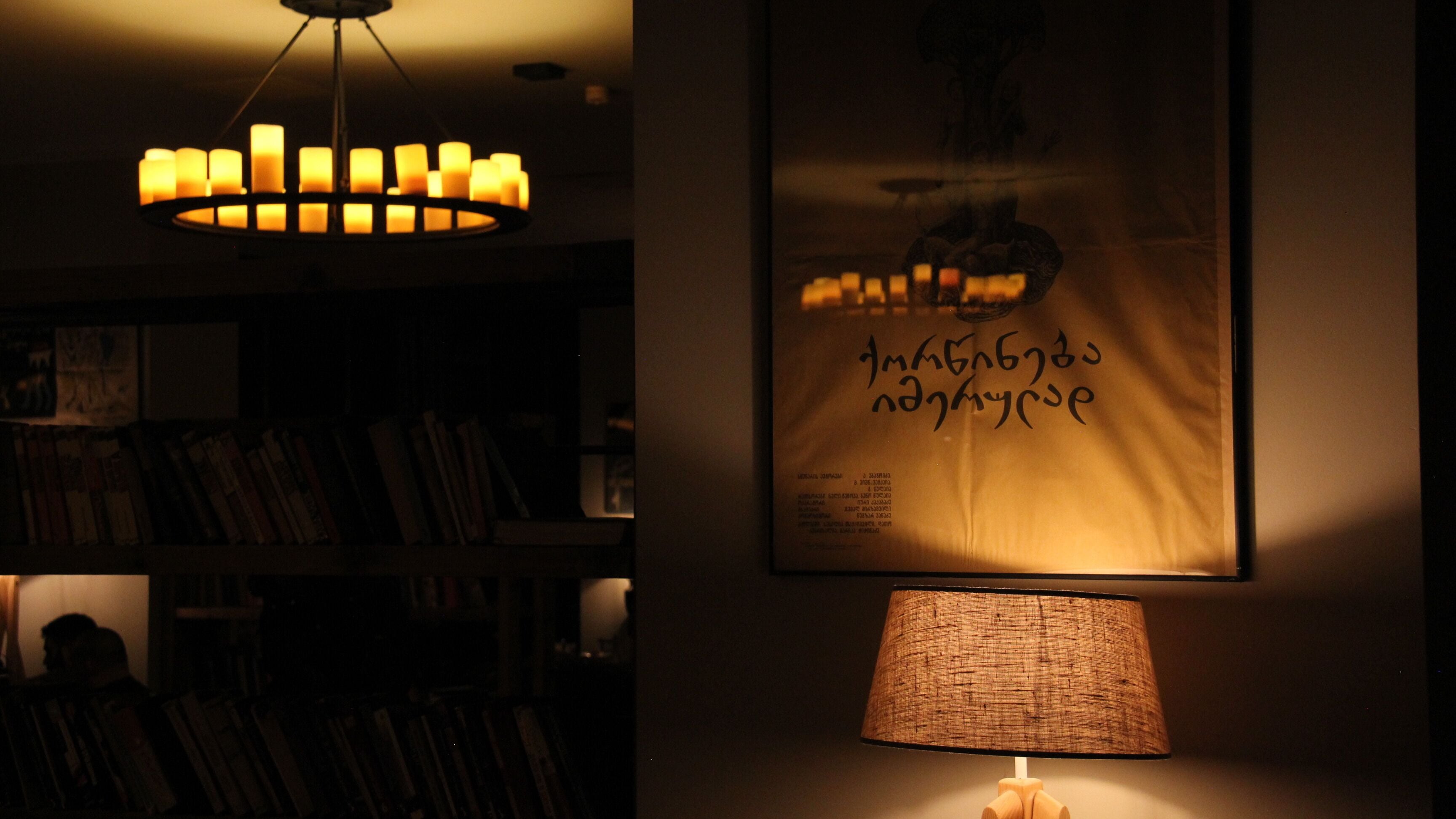 Une pièce faiblement éclairée, avec une lampe fixée au mur et un lustre.