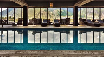 Zona de piscina con sillones de descanso y vistas a montañas.