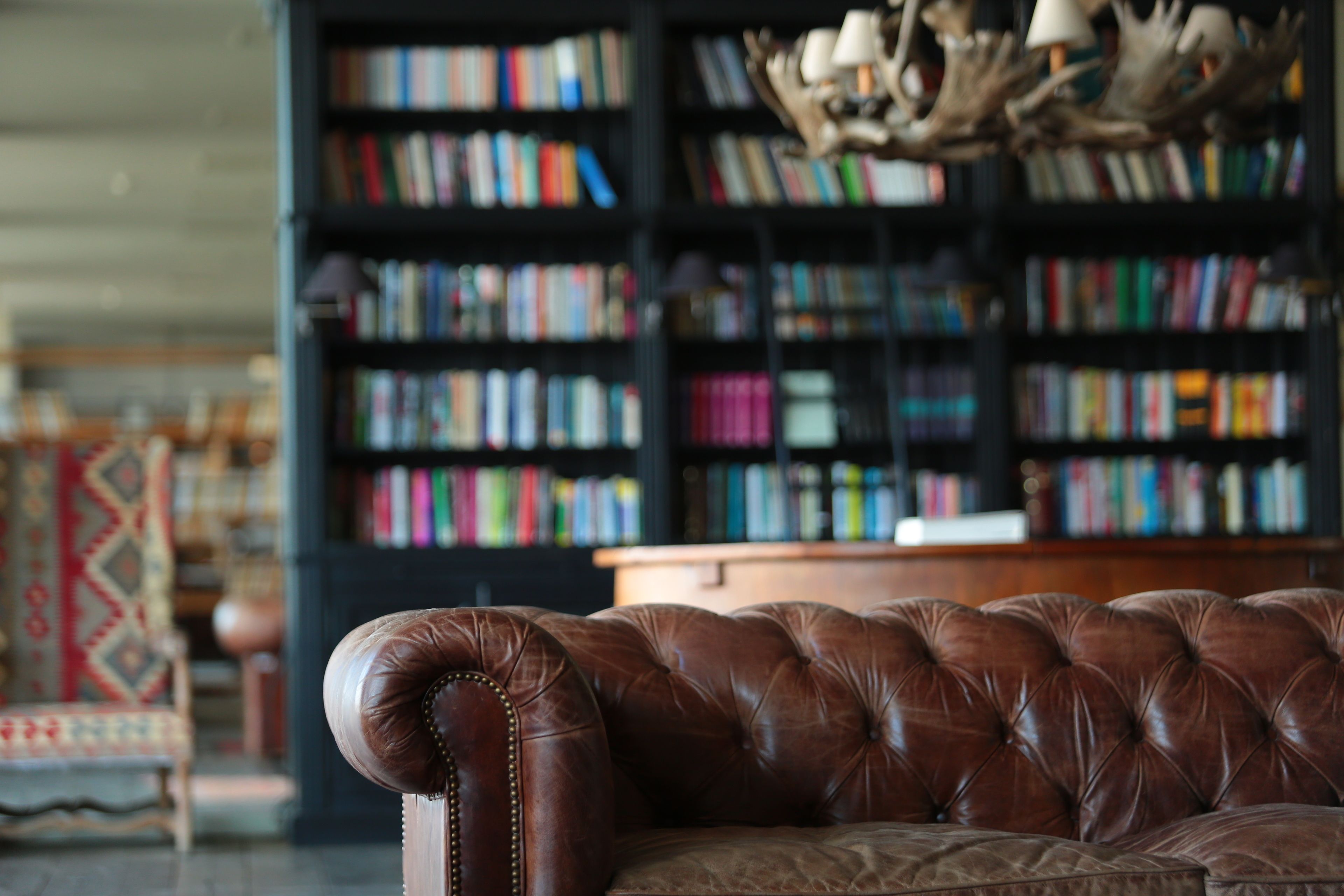 A leather sofa in a room with a bookshelf filled with books.