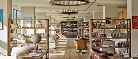 A spacious library with wooden bookshelves, a central seating area, and a large globe on a table.