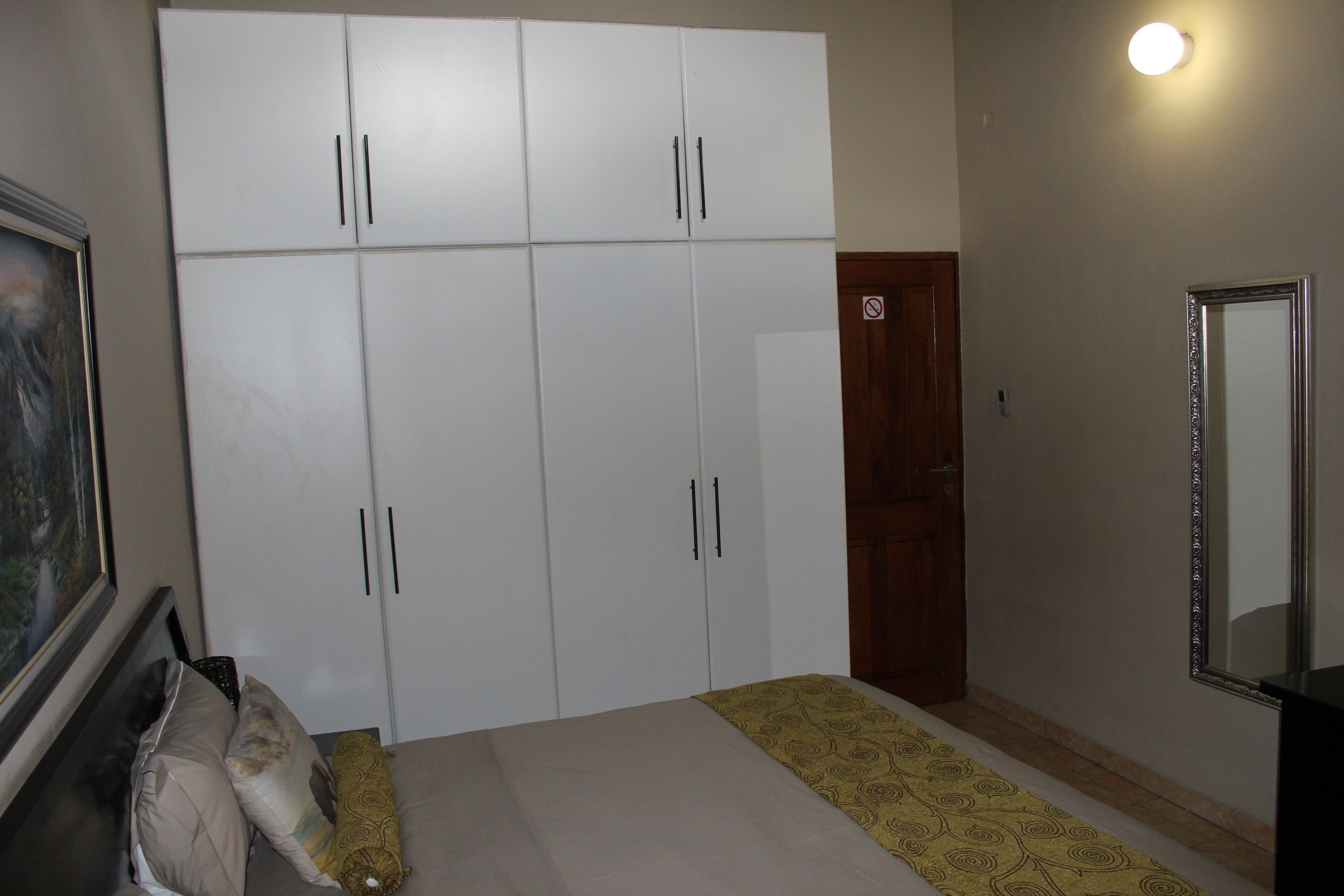 Un dormitorio con una cama, un armario, un espejo y un cuadro en la pared.