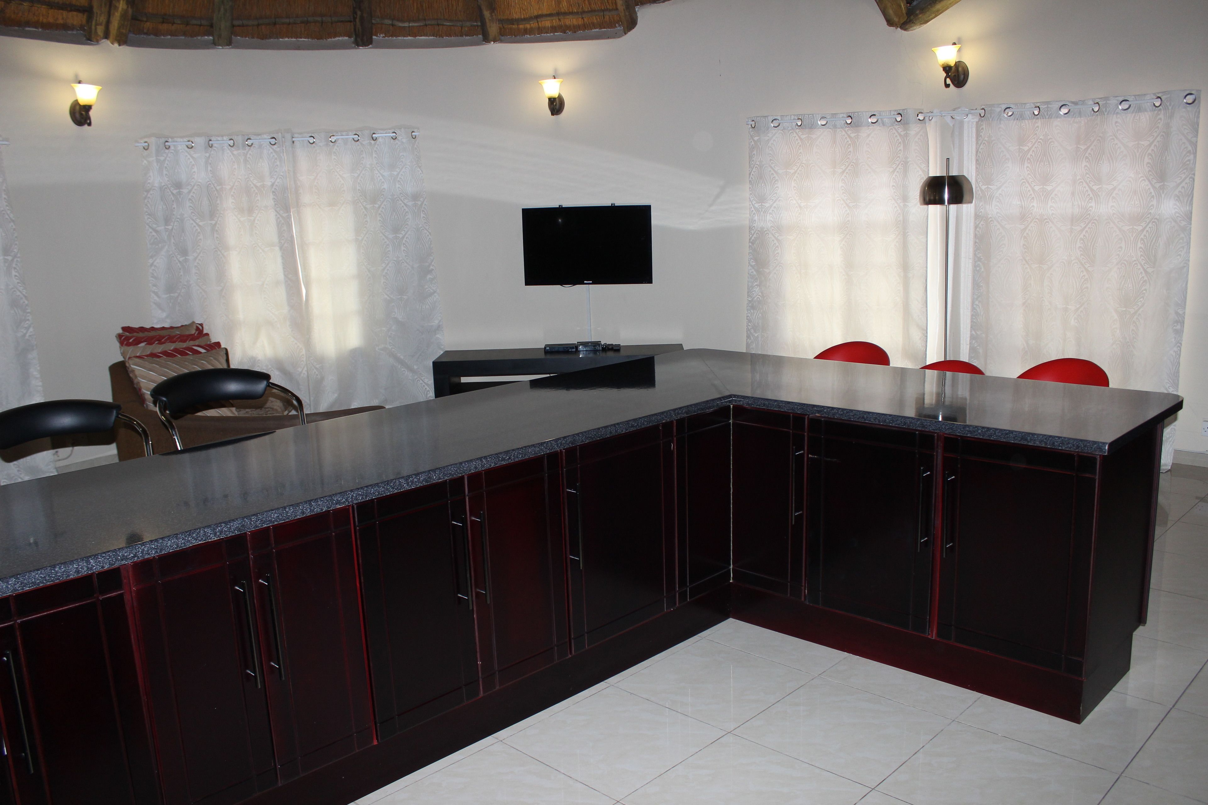 A modern kitchen with dark cabinetry, a large island, and a flat-screen TV.