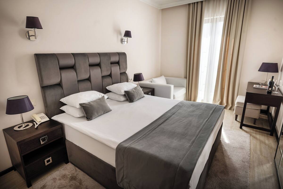 A hotel room with a large bed, bedside tables, a desk, and a chair.