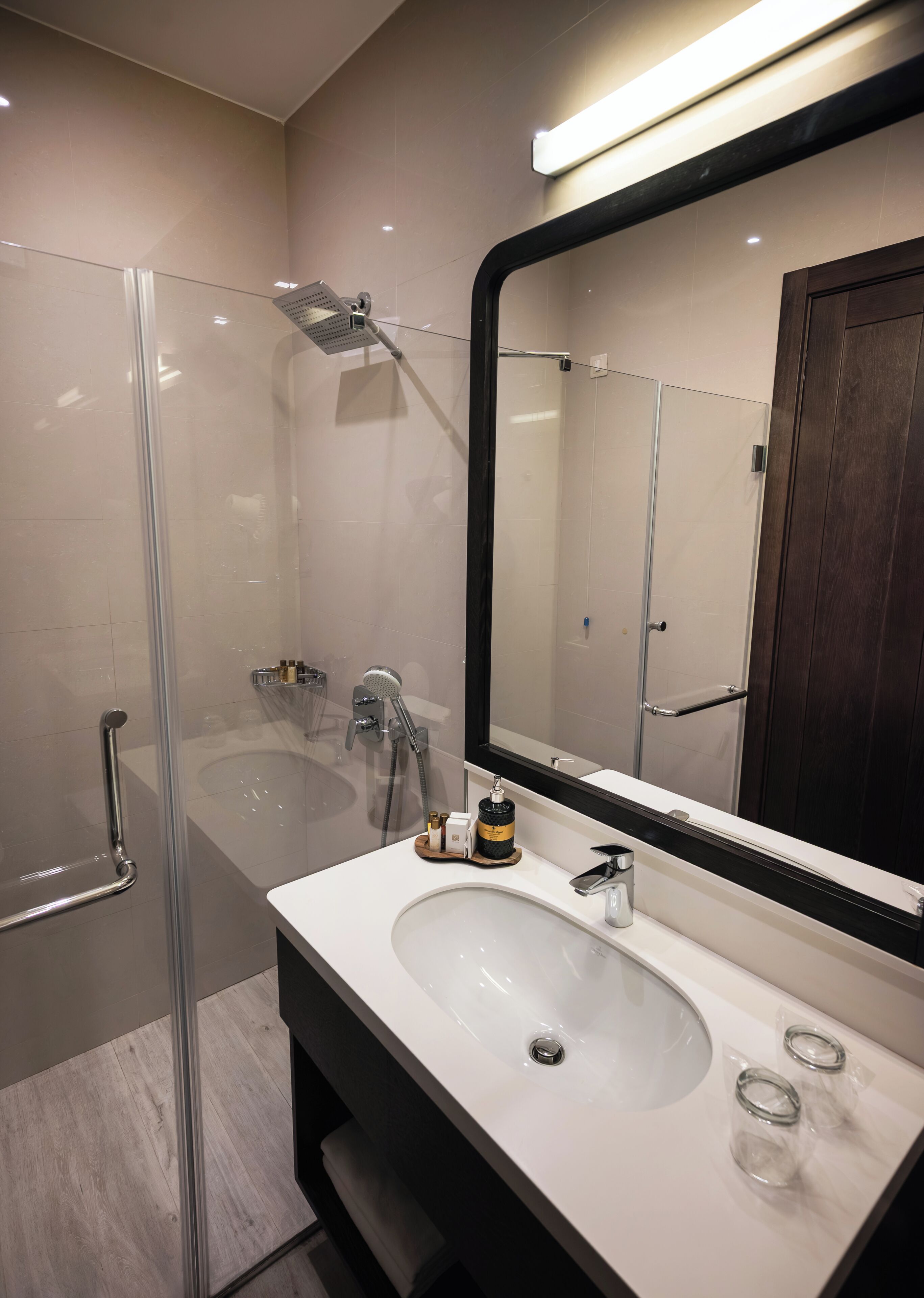 A modern bathroom with a glass shower enclosure, a white sink, and a large mirror.