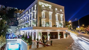 A multi-story hotel with a prominent sign, outdoor seating area, and a visible garage entrance. - Hotel Moskva (Budva)