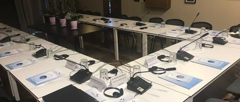 A conference room with long tables, nameplates, laptops, and various office supplies.