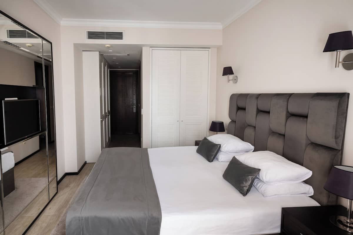 A hotel room with a large bed, a television, a wardrobe, and a mirror.
