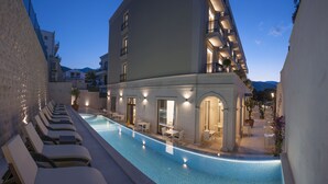 Un hotel con piscina, sillas de descanso y zona de estar al aire libre.