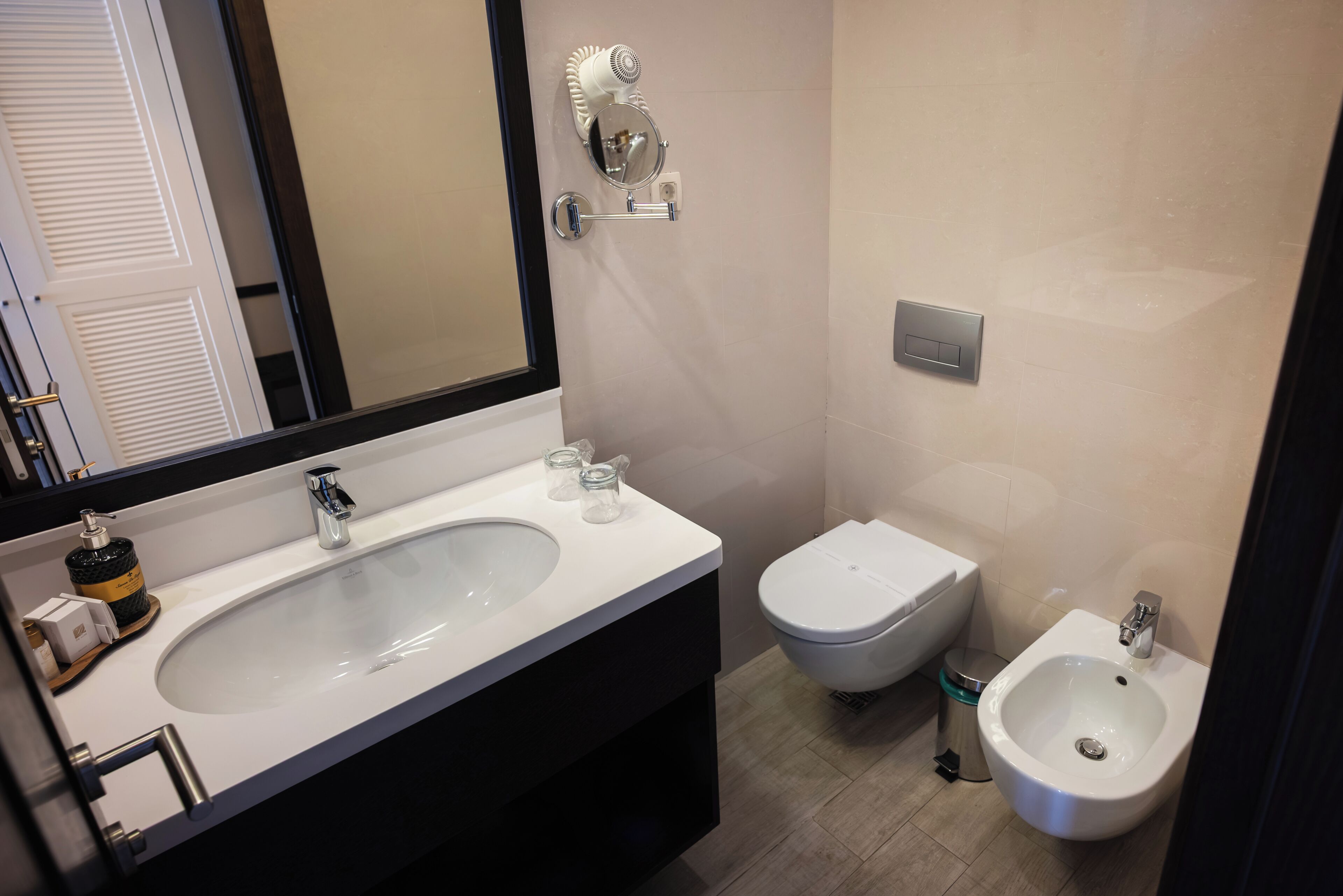 A bathroom with a large sink, a bidet, a toilet, and a mirror.
