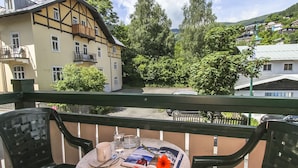 A balcony with a table set for two, featuring a book, a flower, and glasses. - Appartements Trinker (Zell am See)