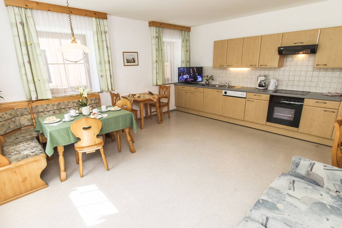 A cozy kitchen with wooden cabinets, a dining table set for four, and a built-in oven.