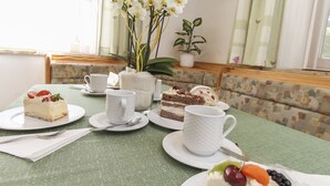 A table set with a slice of cake, a cup, and a fruit arrangement. - Appartements Trinker (Zell am See)