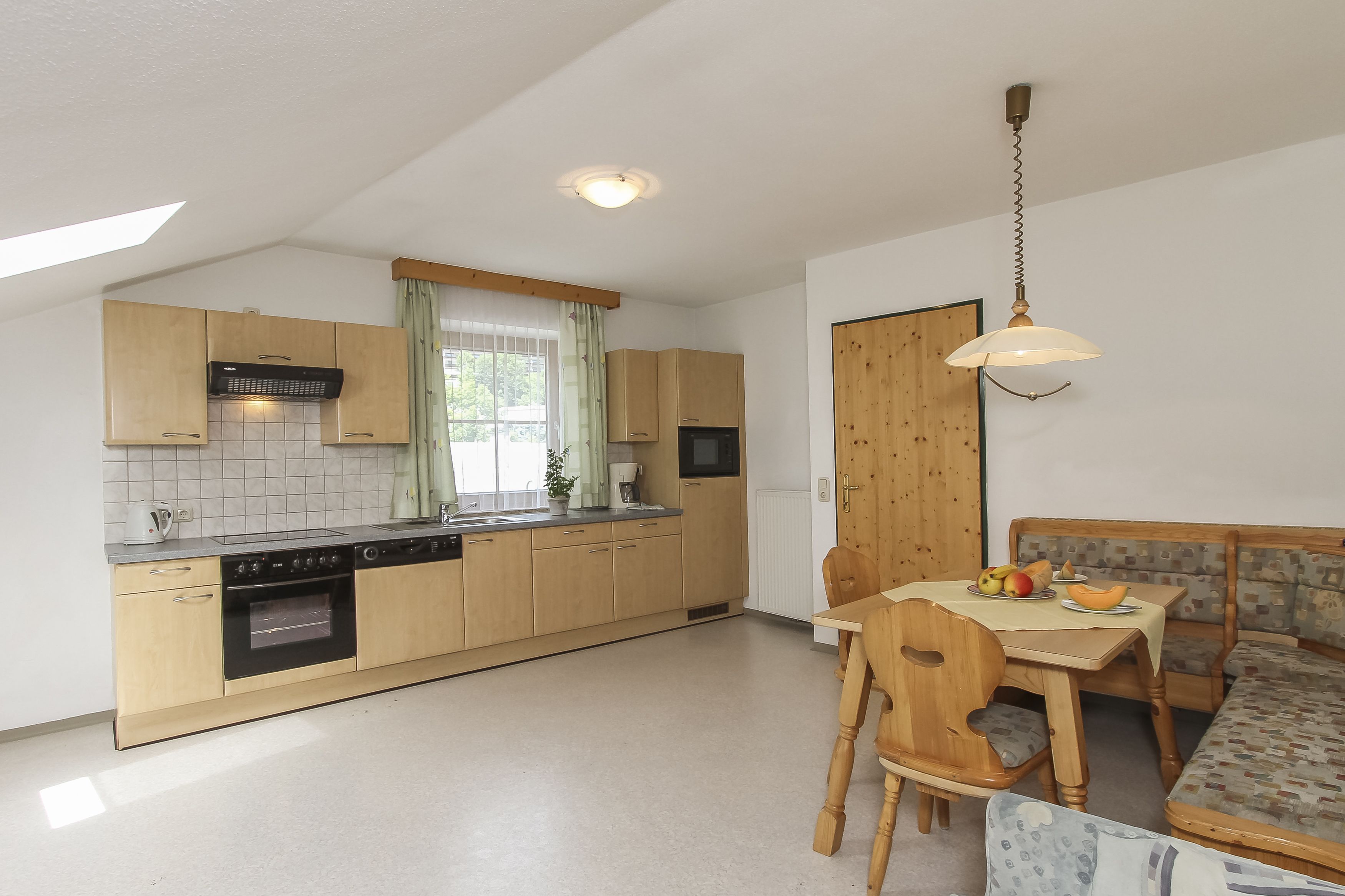 A kitchen with wooden cabinets, a built-in oven, and a dining area with a wooden table and chairs.