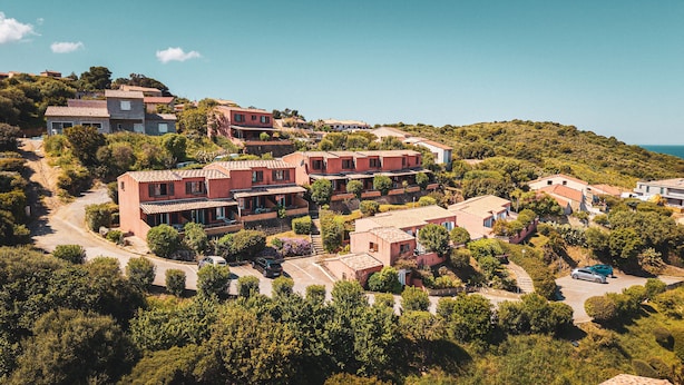 Un barrio residencial en una ladera con casas escalonadas, un camino sinuoso y una vista despejada del mar.