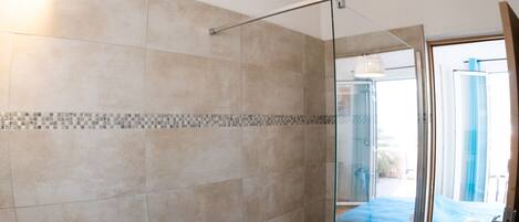 A modern bathroom with a glass shower enclosure, a stone sink, and a tiled shower area.