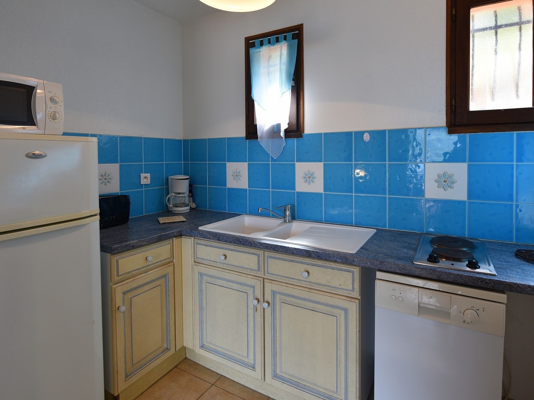 Una cucina compatta con un frigorifero bianco, una macchina del caffè e un lavandino.
