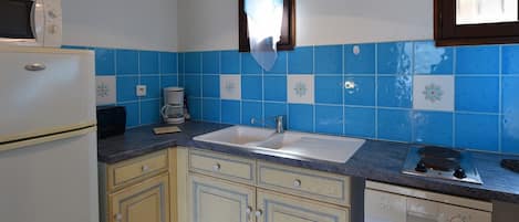 Een kleine keuken met een witte koelkast, een koffiezetapparaat en een spoelbak.