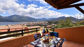 Una terraza con una mesa lista para el desayuno, con vistas a un paisaje de montañas y un lago.