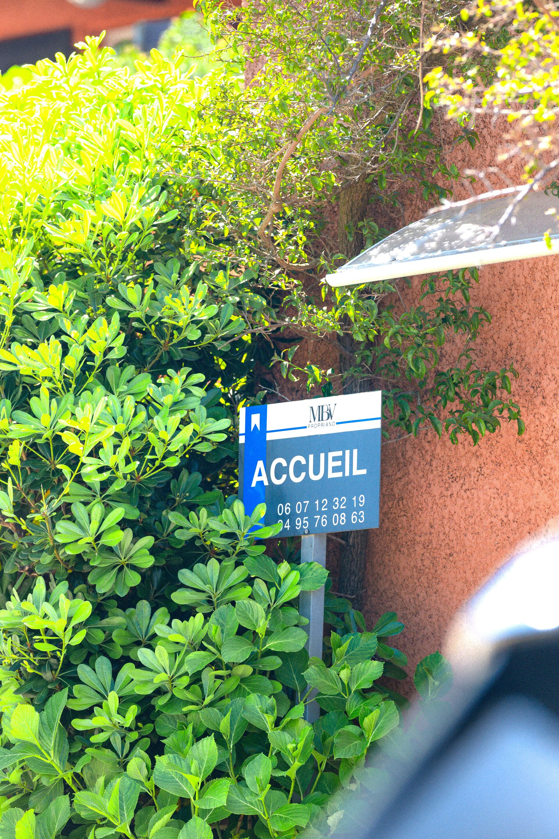 A sign for a hotel named "Accueil" with contact numbers.
