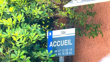 Een bord met de naam van een hotel, 'Accueil', en contactnummers.