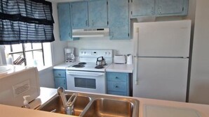 Une cuisine avec des meubles de couleur bleu clair, une cuisinière blanche et un réfrigérateur blanc.