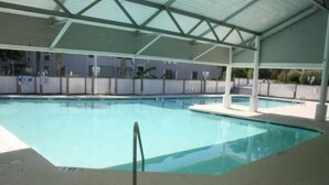 An indoor swimming pool with a covered area, clear water, and a metal safety railing. - Lake Arrowhead Pad (Myrtle Beach)